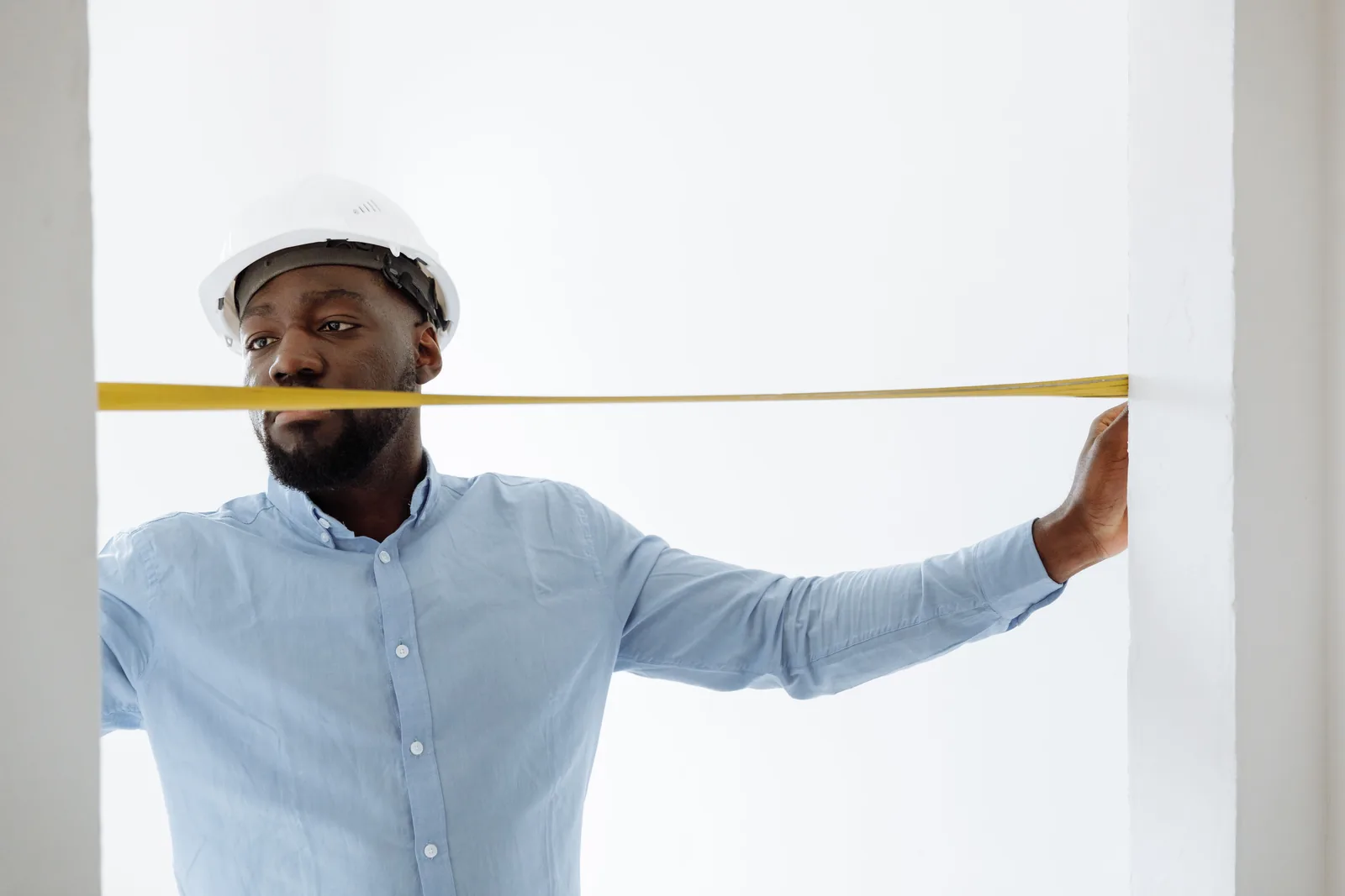 Handyman measuring a kitchen cabinet with a tape measure before quoting